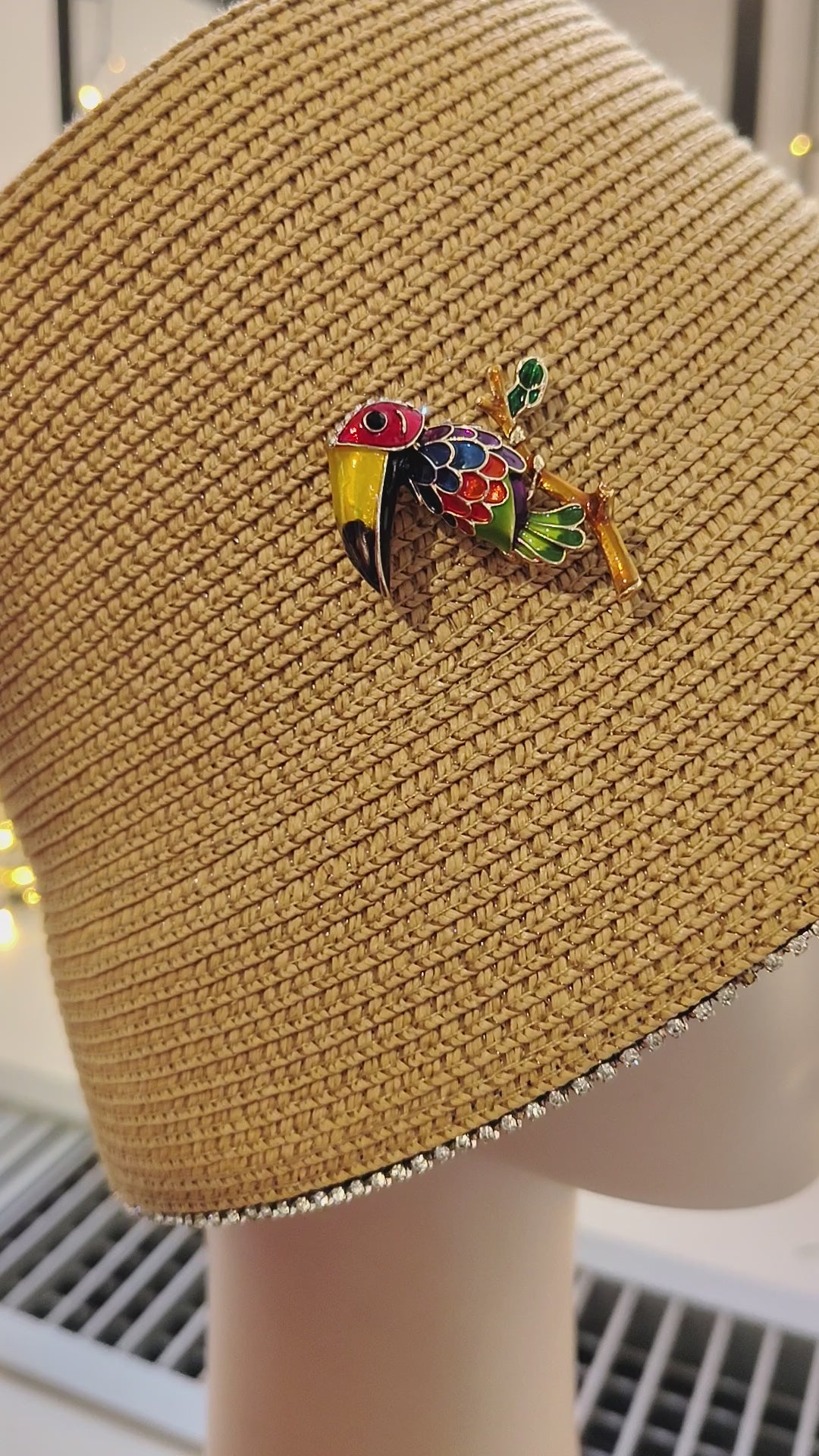 Handmade couture hat in textile paper with colorful toucan jewel brooch, artisan Made in Italy fashion accessory.